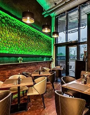 restaurace se zelenou stěnou a dřevěnými stoly a židlemi a bar s televizí na stěně, mechová stěna, mechové dekorace, obraz z mechu, mechová zeď, mechovy obraz, dekorativní mech