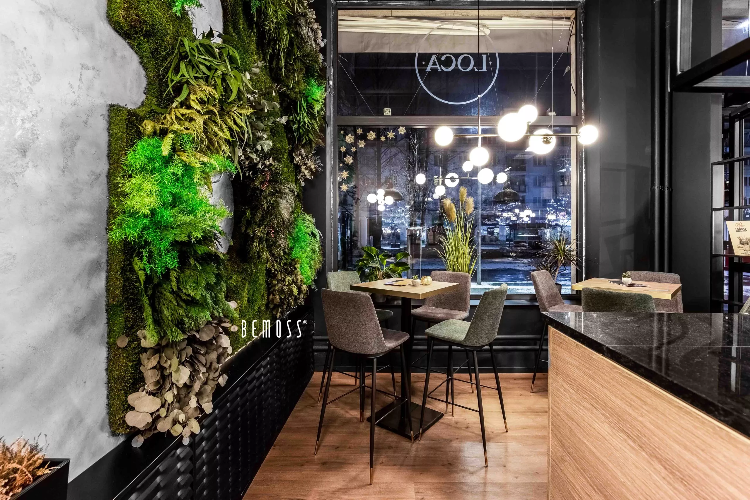 restaurace s mechovou stěnou a jídelním stolem a židlemi s černou pracovní deskou a dřevěnou podlahou, mechová stěna, mechové dekorace, obraz z mechu, mechová zeď, mechovy obraz, dekorativní mech
