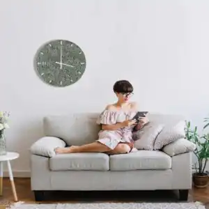 žena sediaca na gauči s tabletom v ruke a hodinami na stene za sebou machovy obraz, stabilizovany mach, machová stena, machová dekorácia
